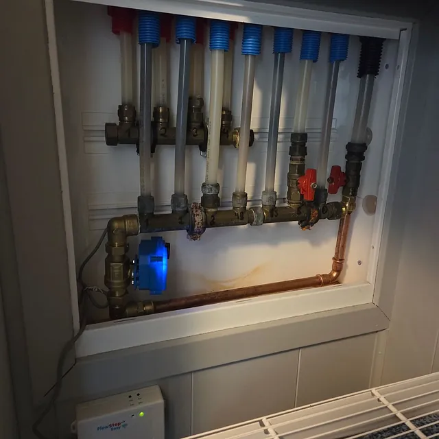 Fordelerskap for vannrør med rørfordeler, kobberrør, avstengningsventiler og lekkasjesikring installert i vegg.